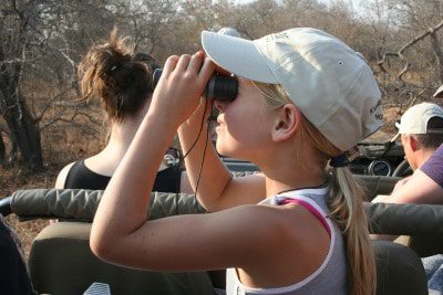 Op safari met jonge kinderen - Meisje kijkt door verrekijker op game drive