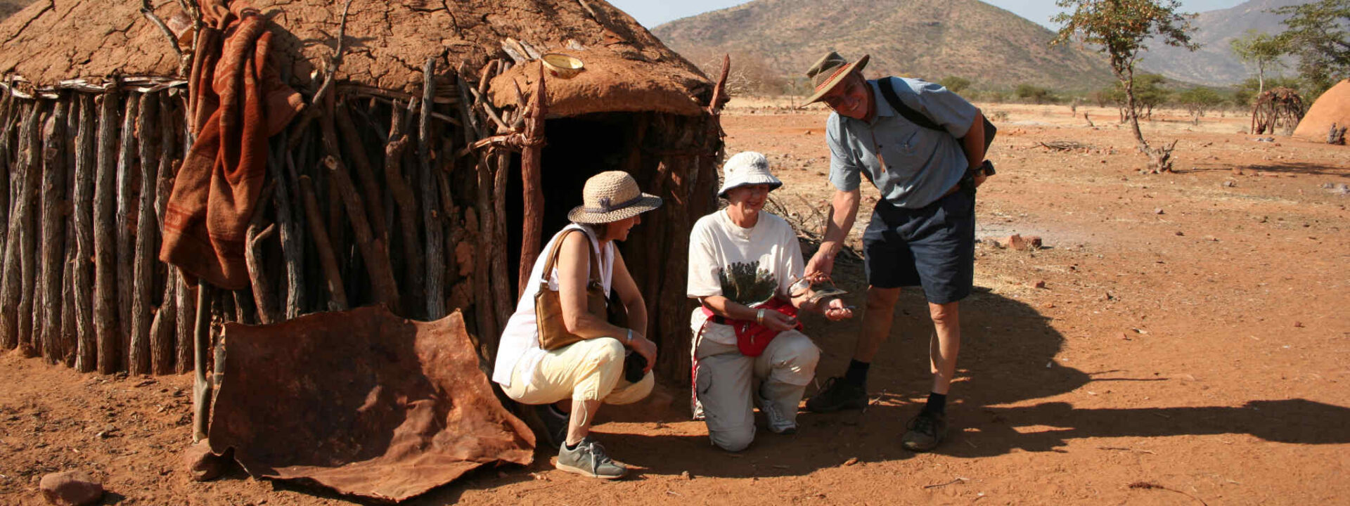 Toeristen brengen een bezoek aan een Himba dorp in Namibië