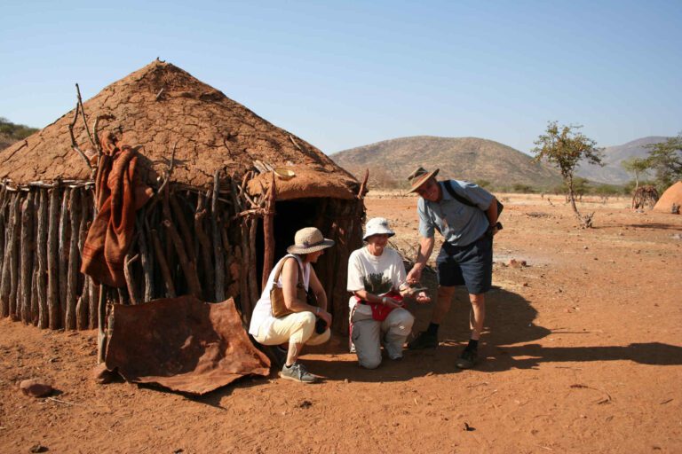 Toeristen brengen een bezoek aan een Himba dorp in Namibië