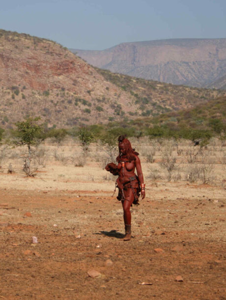 Himba vrouw loopt door het landschap in Epupa, Namibië