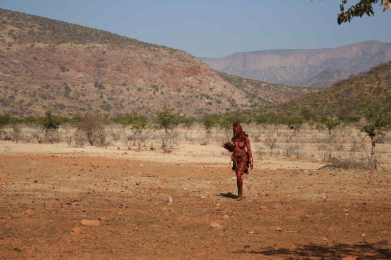 Himba vrouw loopt door het landschap in Epupa, Namibië