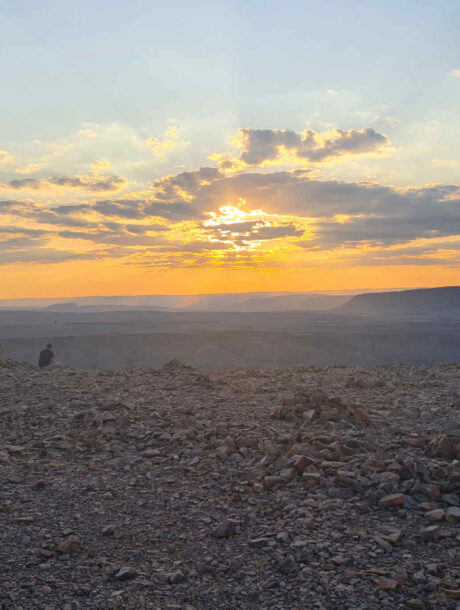Zonsondergang over de Fish River Canyon met een man die uitkijkt over de vallei