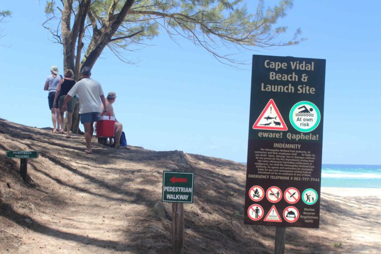 Mensen op weg naar het strand van Cape Vidal in Isimangaliso Wetlands met waarschuwingsborden