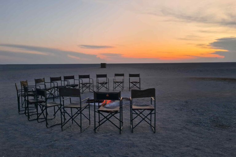 Kampeerstoelen bij het kampvuur tijdens zonsondergang op de Makgadikgadi Zoutpannen in Botswana