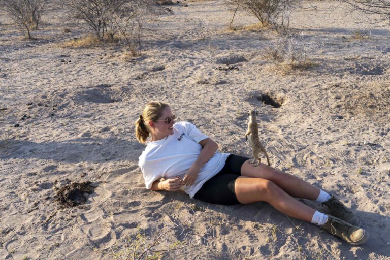 Vrouw met een stokstaartje op haar benen in de Makgadikgadi Zoutpannen