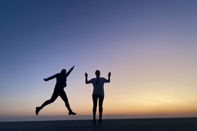 Vrouwen springen tijdens zonsondergang op de Makgadikgadi Zoutpannen